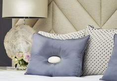 a bed with two pillows and a lamp on the side table next to each other