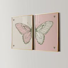 two pink and white butterfly paintings hanging on the wall