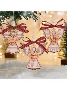 three wooden angel ornament hanging from a christmas tree with red and white ribbon