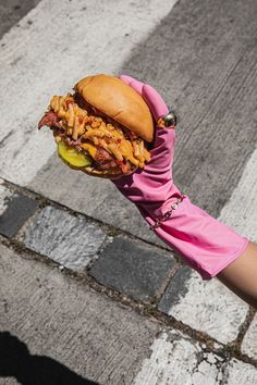 a person in pink gloves holding up a large hamburger