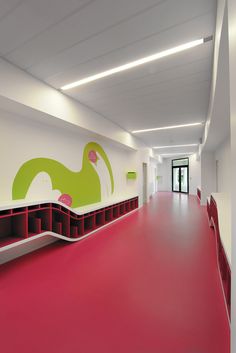 an empty hallway with red carpet and white walls, painted in bright green and pink