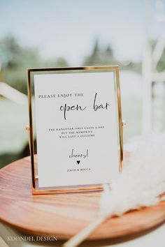 a close up of a sign on a table with a white feather in front of it