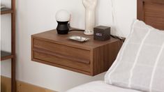 a nightstand with an alarm clock on it next to a night stand and lamp in a bedroom