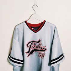 Vintage y2k silver / white / black Fubu jersey. FUBU 05 Jersey. FUBU 05 graphic logo on chest and back. embroidered badges on sleeve and chest. FUBU ATHLETICS 1992  Fubu jersey Fubu top Fubu shirt Fubu t shirt P2P 28 INCH, LENGTH 34 INCH Size XXL Good condition  UK AND WORLDWIDE SHIPPING SERVICE  FULLY TRACKABLE SHIPPING SERVICE Streetwear Short Sleeve Jersey With Team Logo, Short Sleeve Jersey With Team Logo For Streetwear, Team-colored Graphic Print Jersey For Streetwear, Collegiate Jersey For Streetwear During Sports Season, White Jersey With Team Logo For Streetwear, White Team Logo Top For Streetwear, Varsity Streetwear Tops With Embroidered Graphics, White Baseball Jersey With Team Logo For Streetwear, White Streetwear Top With Team Logo