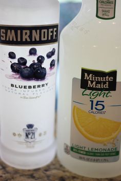 two bottles of blueberries and lemonade sitting on a counter next to each other