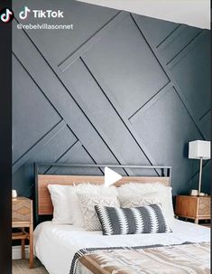 a bed with white and black pillows in a bedroom next to a wooden night stand