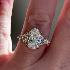 a woman's hand with a three stone ring on it, and the middle finger is