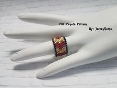 a hand with a ring on it that has beaded beads in the shape of hearts