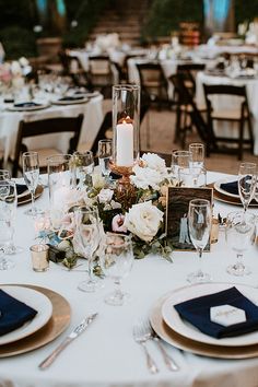 the table is set with white and blue linens, silverware, and candles