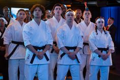 a group of people standing next to each other in front of a crowd wearing white uniforms