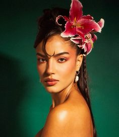 a woman with flowers in her hair is posing for the camera and wearing a flower in her hair