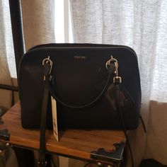 Beautiful New Black Purse. Approx. 18" W X 12" H. Interior Has 2 Large Sections Divided By Zipper Compartment Along With 2nd Small Zipper Compartment. Material Is Man Made With Cross Grain Appearance. See Last Picture. Elegant Calvin Klein Shoulder Bag With Zipper Closure, Elegant Calvin Klein Shoulder Bag With Zipper, Black Calvin Klein Bag For Formal Occasions, Calvin Klein Black Formal Bag, Elegant Calvin Klein Bag With Branded Hardware, Elegant Calvin Klein Shoulder Bag For Formal Occasions, Classic Calvin Klein Formal Bag, Chic Formal Calvin Klein Shoulder Bag, Calvin Klein Black Business Bags