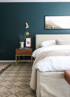 a bedroom with teal walls and white bedding