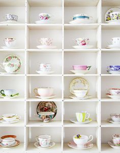 a white shelf filled with lots of cups and saucers