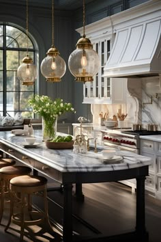 a kitchen with marble counter tops and pendant lights hanging from the ceiling over the island