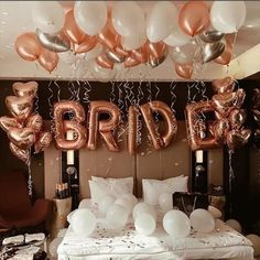 a bed topped with lots of white and gold balloons