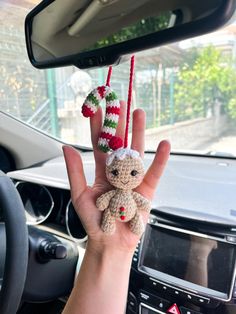 a person holding up a small stuffed animal in their hand with christmas decorations hanging from it's palm