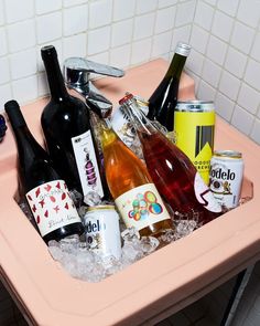 a sink filled with lots of different types of drinks and liquor in ice cubes