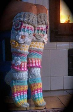 a woman's legs wearing colorful knitted socks with flowers on them and one leg in the air