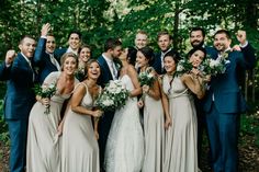 a group of people standing next to each other in front of some trees and bushes