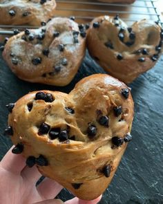 a person holding up a heart shaped chocolate chip muffin