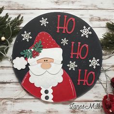 a black and red plaque with santa clause on it's face, surrounded by christmas decorations