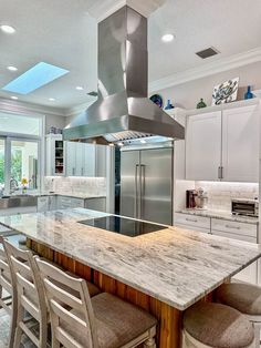 a large kitchen with an island and stainless steel oven hood over the stove, surrounded by stools