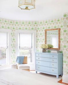 a bedroom with floral wallpaper and blue dresser