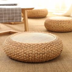 two woven stools sitting on top of a carpet next to a chair and table