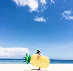 a person standing on the beach with a large piece of fruit in front of them