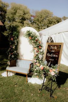 a sign that is sitting in the grass next to a chair and some flowers on it