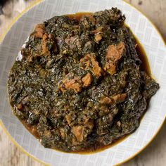 a white bowl filled with greens and meat