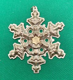 a metal snowflake ornament on a green background