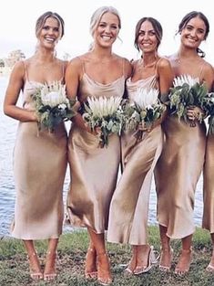 the bridesmaids are all wearing gold dresses and holding bouquets in their hands