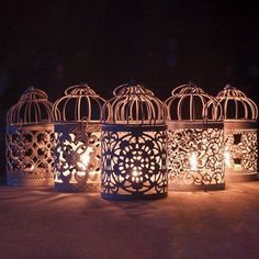 four decorative birdcages with candles in them sitting on a table next to each other