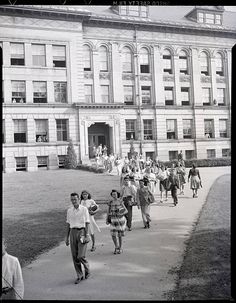 an old black and white photo of people walking in front of a building