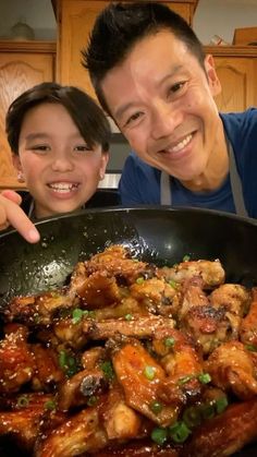 a man and woman posing in front of a pan filled with food