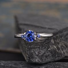 a ring with three blue sapphire stones on it sitting on top of a stone slab