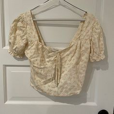 Sweet Floral Crop Top With Bow Detail In Front And Smocking On The Back. Tags Still Attached. Brand New, Never Worn. Side Hidden Zipper Slightly Puffed Short Sleeves Feminine Square Neck Tops For Beach, Floral Print Square Neck Top For Beach, Beige Square Neck Blouse For Spring, Cream Puff Sleeve Blouse For Summer, Casual Square Neck Blouse For Vacation, Square Neck Tops For Beach In Spring, Beige Summer Blouse With Smocked Bodice, Spring Vacation Tops With Square Neck, Floral Print Vacation Tops With Square Neck