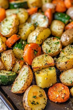 roasted potatoes, carrots and zucchini on a baking sheet with seasoning