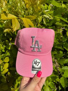 a pink hat with the number 47 on it is held up in front of some bushes