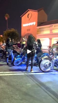 a group of motorcycles parked in front of a building at night with people standing around