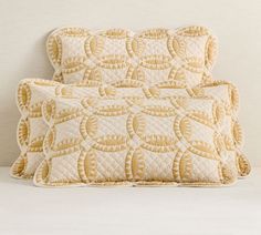 two pillows sitting next to each other on top of a white bedding covered in yellow circles