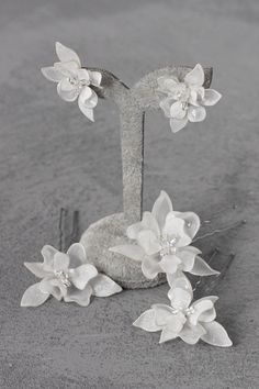 two white flowers are sitting on top of a piece of metal and some hair pins