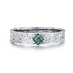 a white gold ring with an emerald stone in the center and filigrees around it