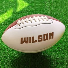 a football sitting on top of a lush green field with the word wilson written on it