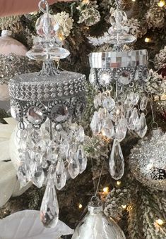 three crystal chandeliers hanging from a christmas tree with white and silver ornaments on it