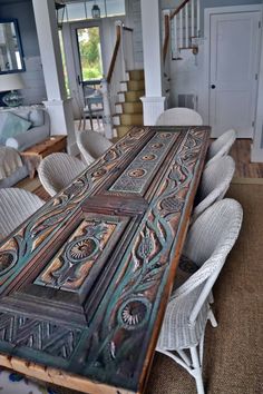 a large wooden table sitting in the middle of a living room next to a stair case