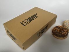 two doughnuts sitting next to each other on a white counter top in a box