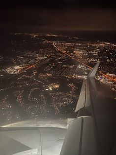 an aerial view of the city lights and streets at night as seen from an airplane window